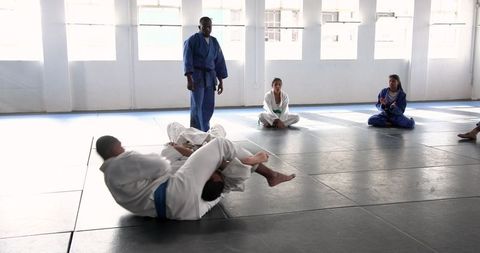 Diverse Martial Arts Class Practicing Techniques on Gray Mat