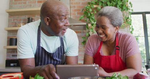 Joyful Senior Couple Enjoys Cooking Through Tablet Recipes