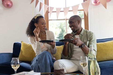 Couple sharing dessert and wine on sofa during intimate at-home birthday celebration