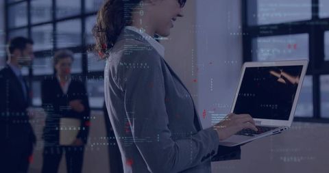 Businesswoman typing on laptop with floating code and data overlays in modern office