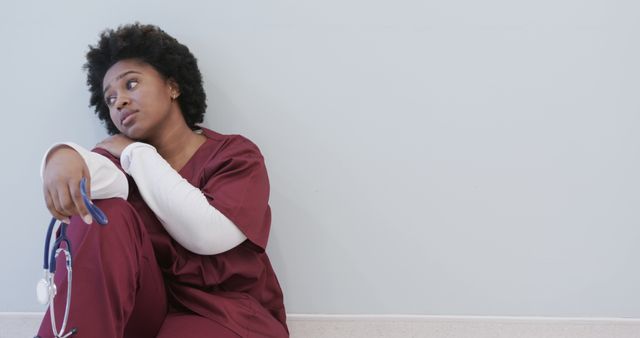 Tired african american female doctor sitting in hospital corridor with copy space, slow motion - Download Free Stock Photos Pikwizard.com