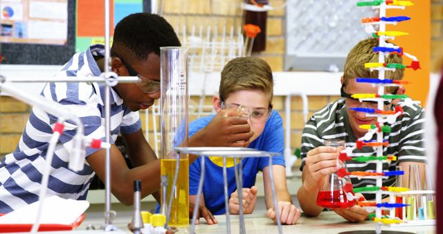 This image shows a group of diverse students engaging in a chemistry experiment in a classroom environment. They are wearing safety glasses and actively participating in mixing chemicals and using laboratory equipment. This could be used for educational materials, science-related articles, school promotions, and advertisements aimed at fostering interest in STEM fields among young students.