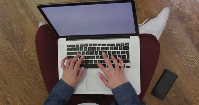 Person Typing on Laptop with Mobile Phone on Wooden Floor - Download Free Stock Images Pikwizard.com