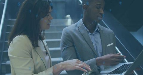Mid-career professionals collaborating on laptop and phone on stair landing with industrial style
