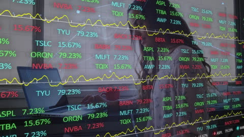 Digital Overlay of Stock Market Data and Businesswoman Typing on Laptop