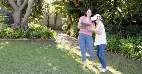 Mother and Daughter Exploring VR Outdoors in Sunlit Backyard