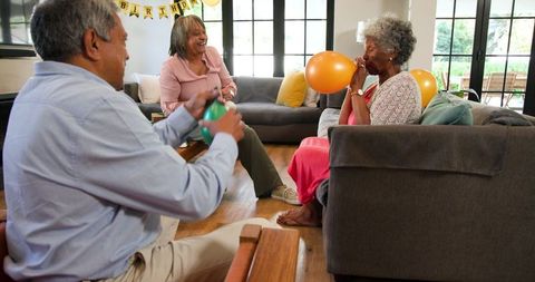 Senior friends joyfully celebrating birthday by inflating balloons