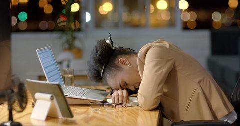 Exhausted Businesswoman Resting Head on Desk at Night Office