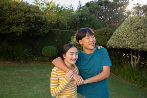 Happy Couple Embracing in Lush Residential Garden at Golden Hour