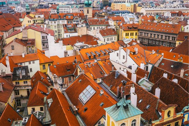 Aerial view of a European city with distinctive red-tiled roofs. The densely packed buildings create a mosaic of architecture with a mix of historic and modern styles. Suitable for illustrating European tourism, cityscapes, travel guides, postcards, and architecture studies.