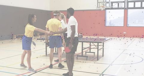 Mixed team shaking hands showing sportsmanship after table tennis match in school gymnasium