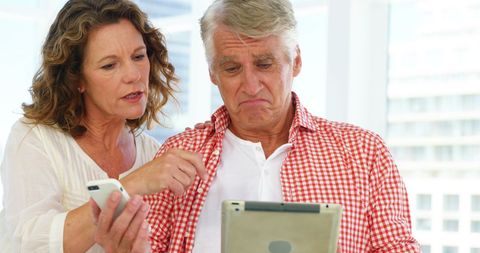 Mature couple using technology devices at home
