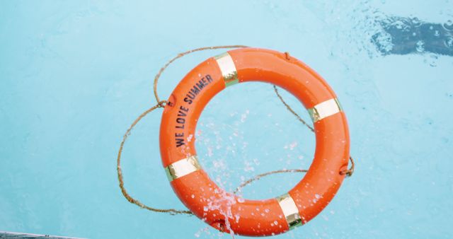 An orange lifebuoy with the phrase We Love Summer floats on the clear blue water of a swimming pool, with copy space. It symbolizes water safety and the enjoyment of summer activities.