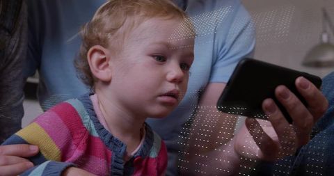 Infant girl watching smartphone while parent holding device, cozy family moment