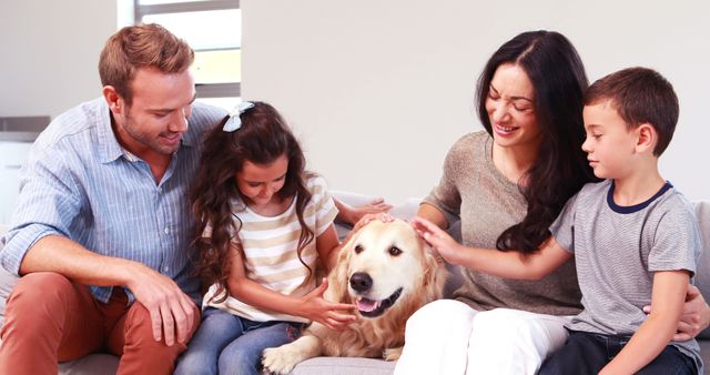 Family of four gathered indoors, lovingly petting their friendly golden retriever. Ideal for promoting pet adoption, family activities, and home lifestyle companies. Demonstrates warmth, care, and close family relationships.