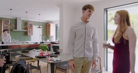 Young adults chatting with drinks in modern open-plan kitchen during casual home gathering
