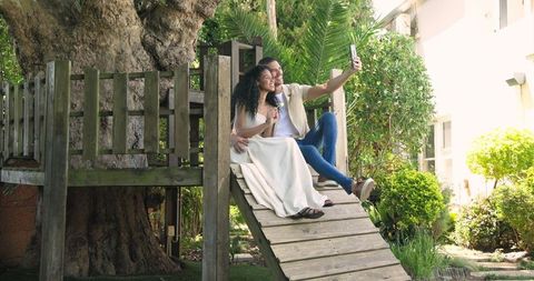 Happy Couple Taking Selfie in Garden Sitting on Wooden Slide