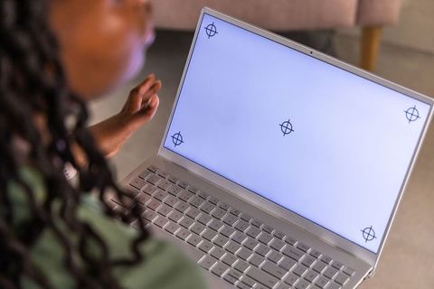 African american woman reaching toward laptop with blank screen crosshairs for remote work