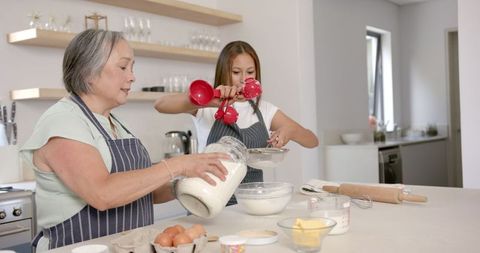 Asian grandmother and child baking together in modern kitchen