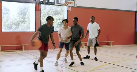 African american basketball players passing and driving on indoor court showing teamwork