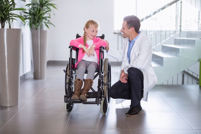 Smiling doctor talking to disable girl in hospital corridor