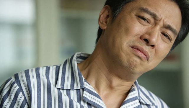 Middle-aged asian man grimacing in striped pajama shirt closeup emotional portrait