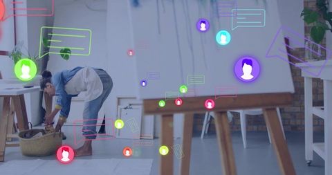 Artist Beside Canvas with Social Media Icons in Creative Studio