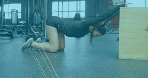 Fitness enthusiast stretching on gym floor next to equipment