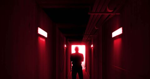 Silhouette of man in eerie red-lit corridor