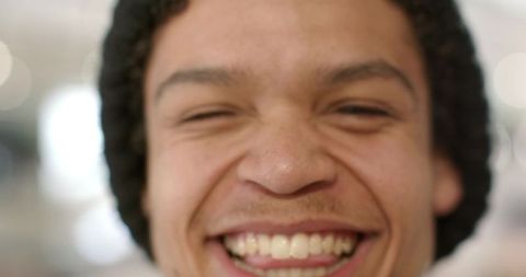 Laughing african american man wearing knit beanie closeup warm smile cafe bokeh