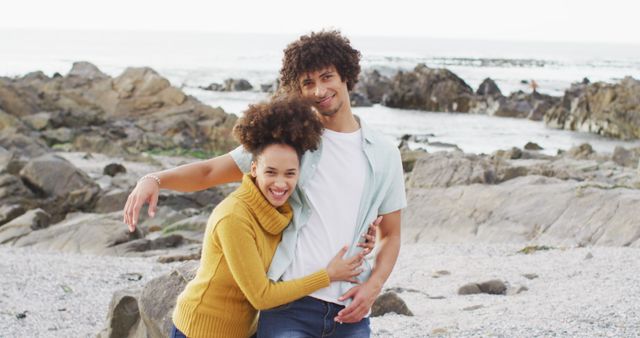 Portrait of african american couple hugging each other on the rocks near the sea - Download Free Stock Photos Pikwizard.com