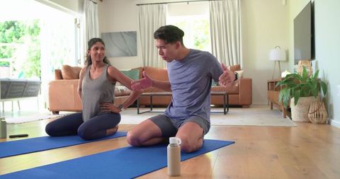 Couple practicing home yoga together on mats in bright living room morning routine