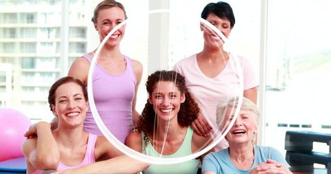 Smiling women posing in bright fitness studio wearing pastel activewear