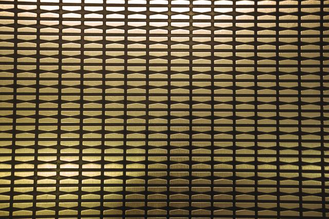 Metallic pattern wall with golden illumination presenting a modern and industrial aesthetic. Suitable for use in design projects, backgrounds for presentations, wallpaper, and architectural concepts.
