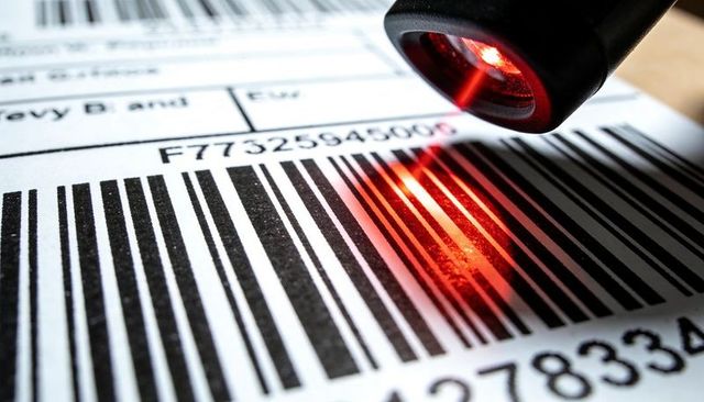Barcode scanner scanning label with red laser beam for inventory tracking and shipping