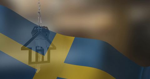 Silver house key hanging over swedish flag symbolizing home ownership