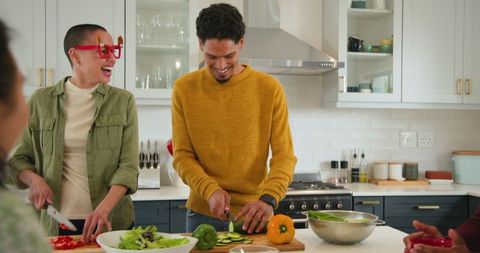 Diverse friends preparing fresh salad together in modern kitchen