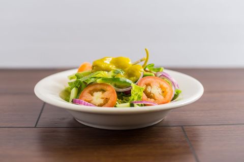 Fresh Garden Salad Featuring Tomato, Red Onion, Lettuce and Pepperoncini with Mustard Dressing