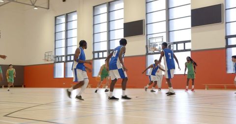 Competitive Basketball Match with Focused Athletes in Modern Gymnasium