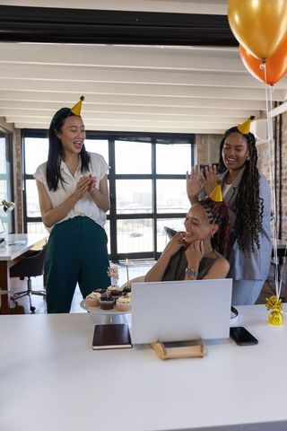 Diverse female coworkers celebrating birthday at modern office