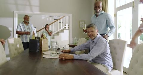 Diverse Senior Friends Celebrating at Home with Drinks and Laughter