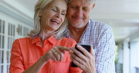 Happy Senior Couple Laughing While Using Smartphone