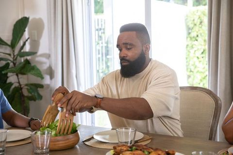 Man Tossing Fresh Salad at Rustic Dining Table