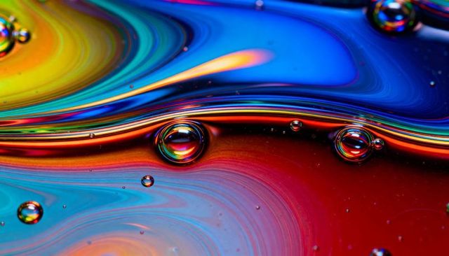 Shimmering iridescent liquid macro flowing rainbow droplets and vivid color swirls