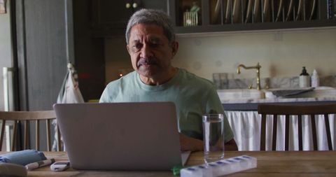 Senior man focused on laptop work at home