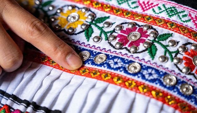 Fingertip pressing embroidered ethnic textile with silver studs on pleated white skirt