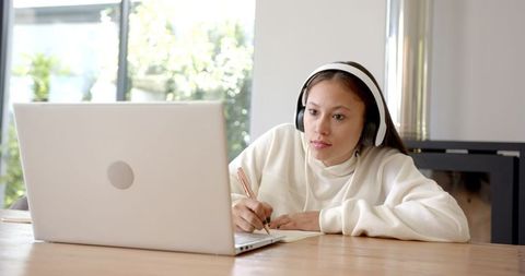 Teenage Girl Studying Online at Home With Laptop and Headphones