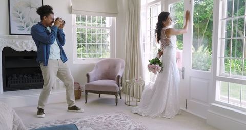 Bride Posing by Window for Romantic Shot with Photographer