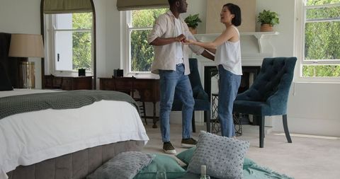 Couple Dancing Playfully in Cozy Bedroom Environment