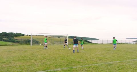 Young Male Soccer Players Training on Sunny Field with Ocean View